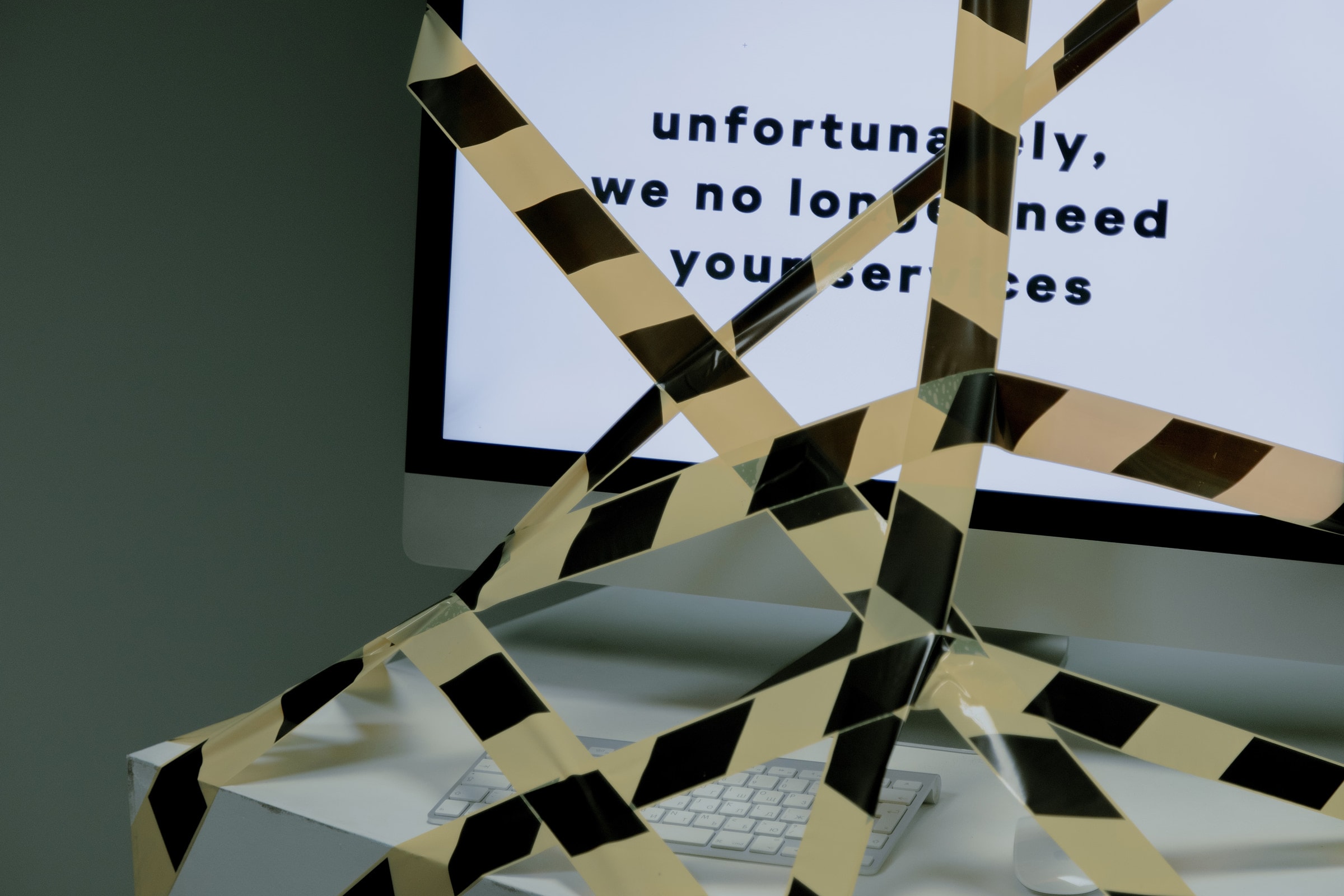 A computer screen taped and displaying a termination message, symbolizing unemployment.