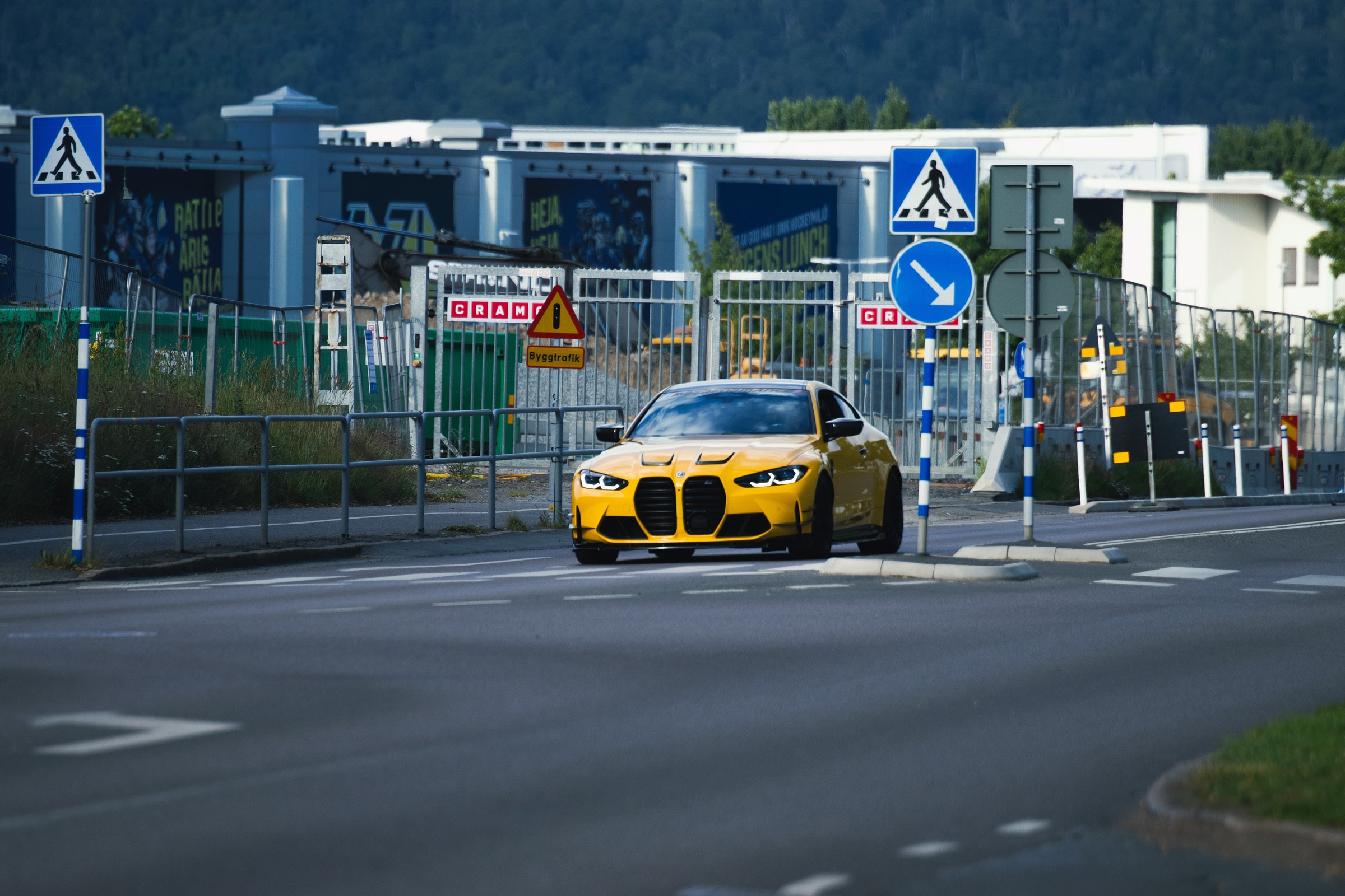 A vibrant yellow sports car travels through an intersection in Jönköping, Sweden, captured in clear daylight.