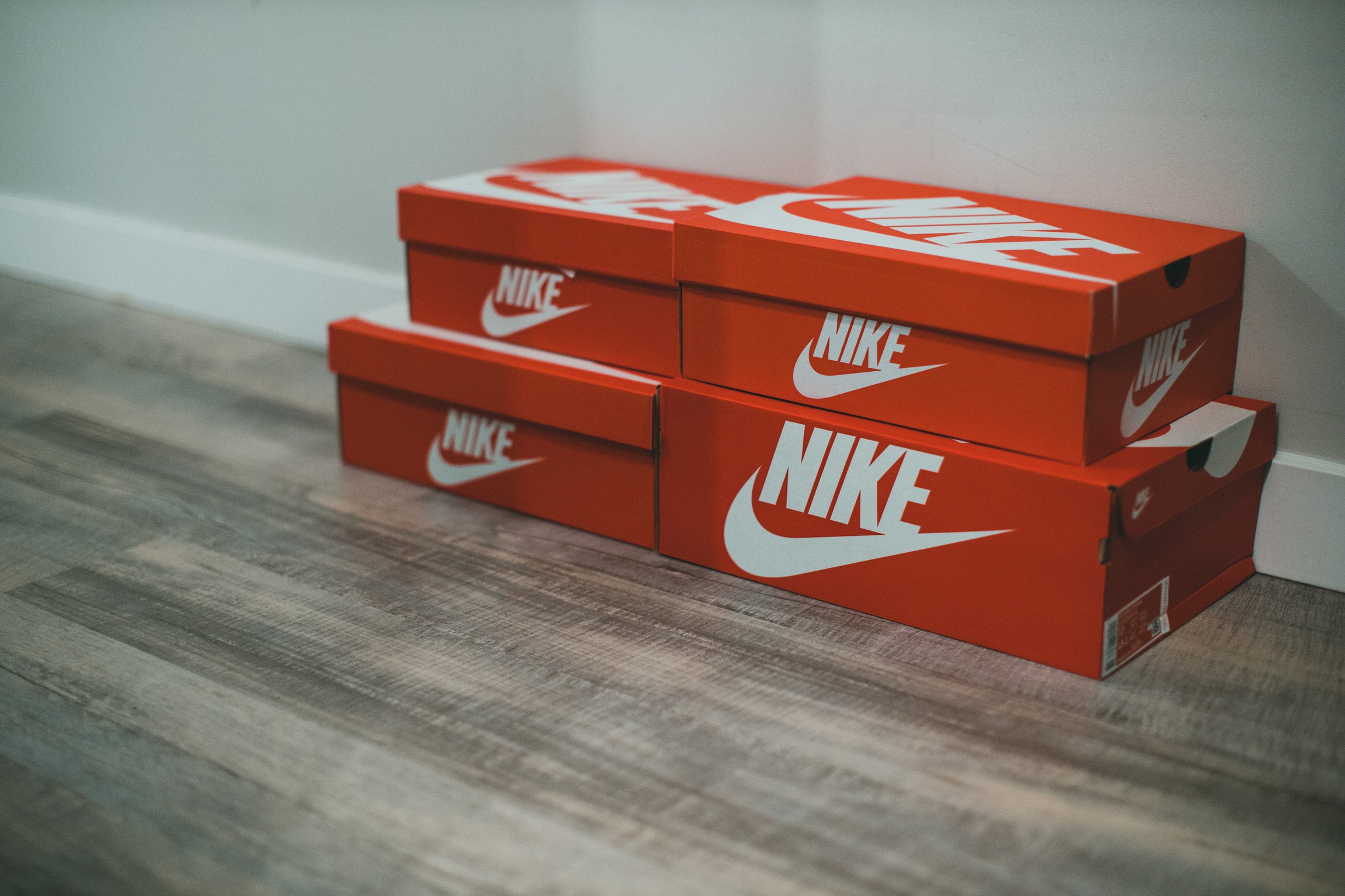 Red Nike shoe boxes stacked neatly on a wooden floor indoors.