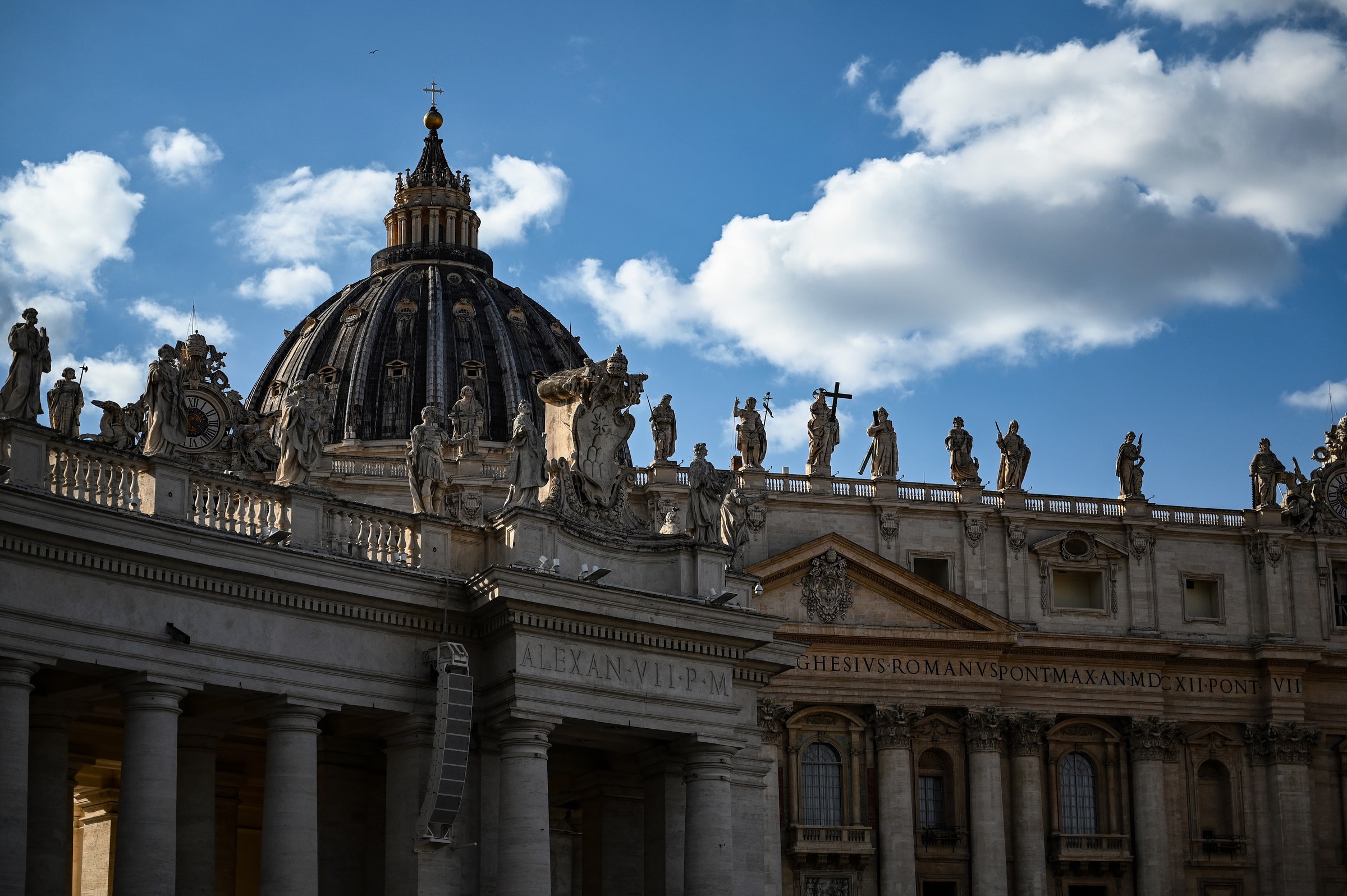Beautiful view of St. Peter's Basilica with statues and blue sky in Vatican City.