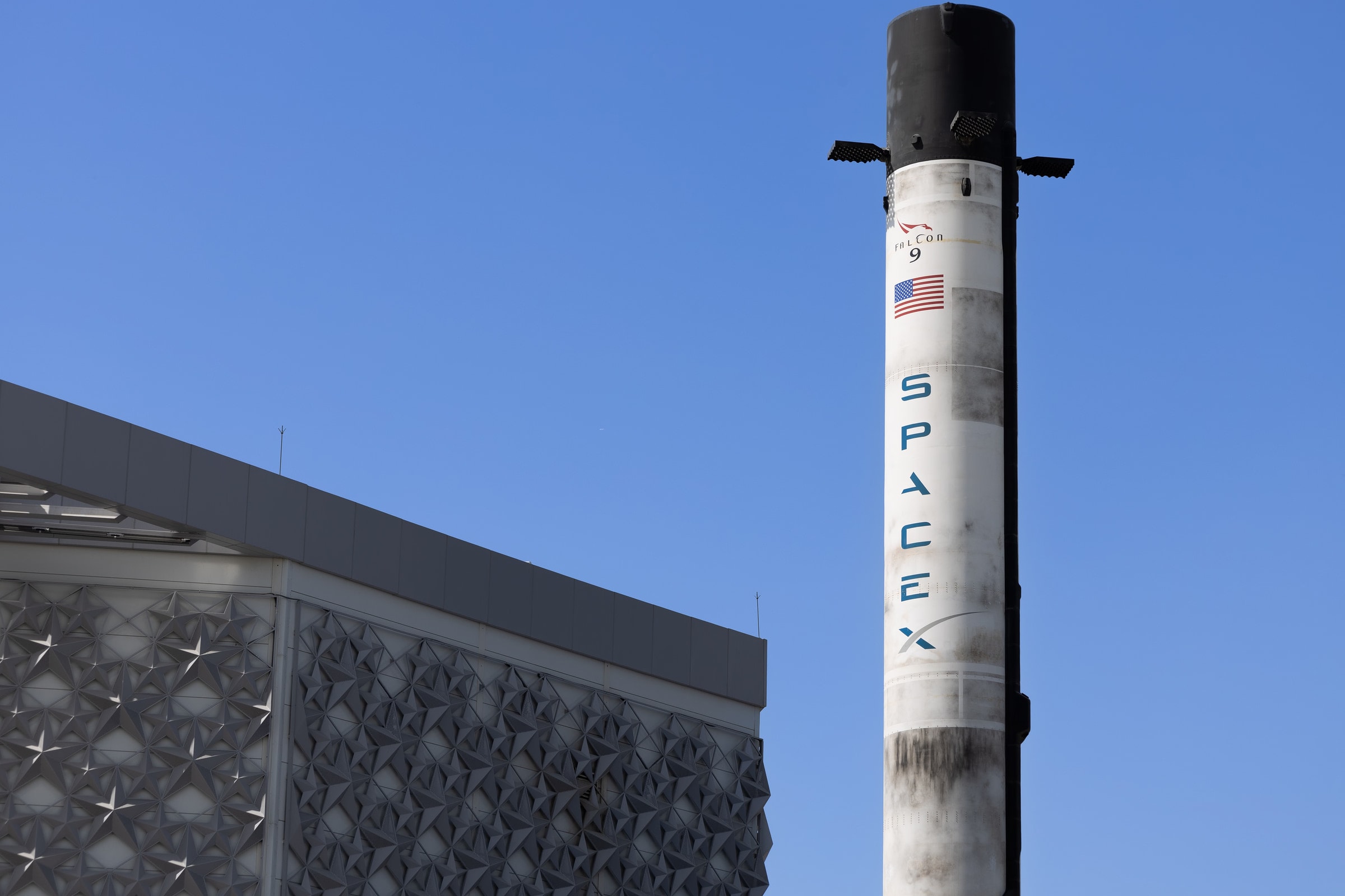 A SpaceX Falcon 9 rocket displayed outdoors against a clear blue sky in Dubai.