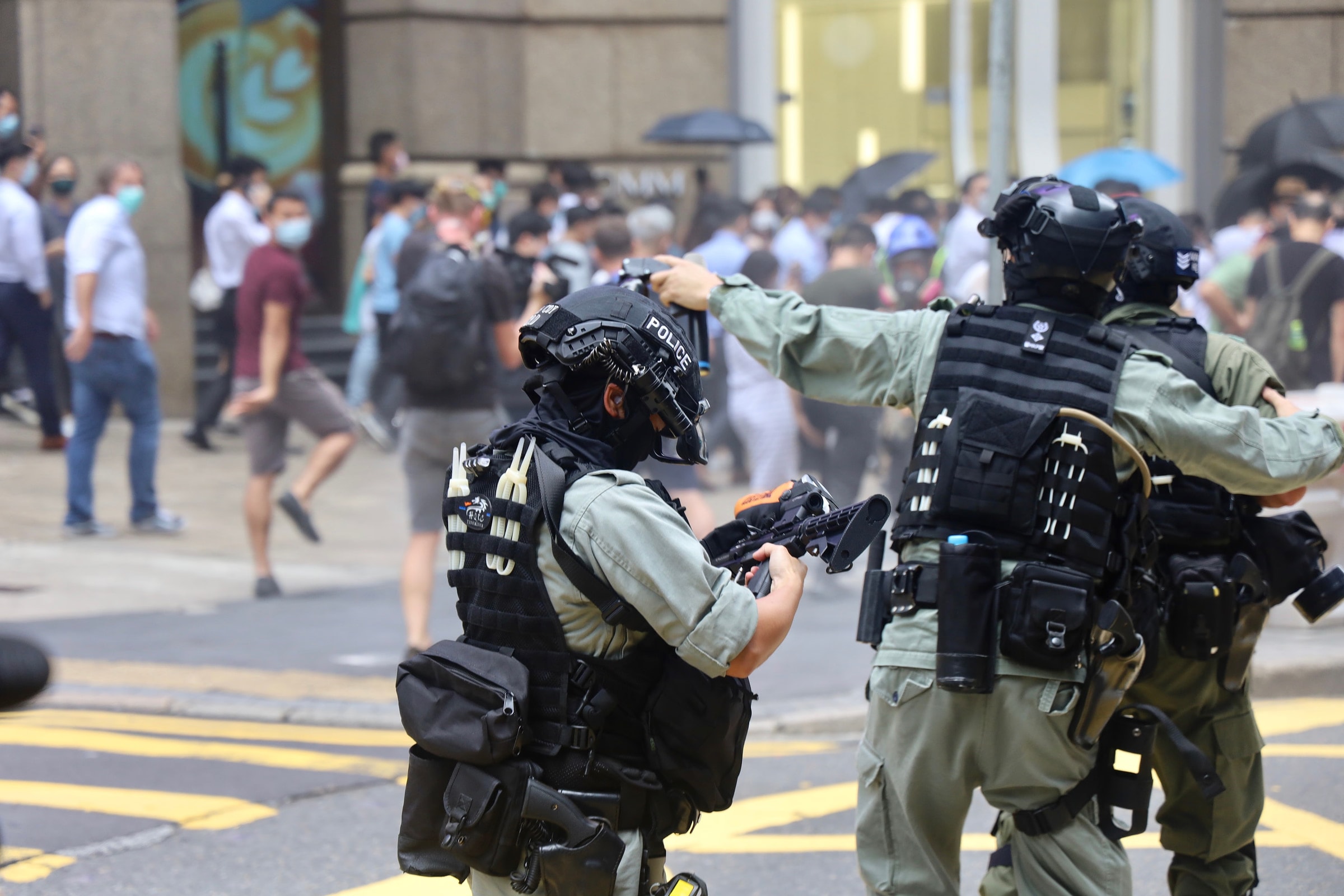 Police officers in protective riot gear during a protest scene outdoors.
